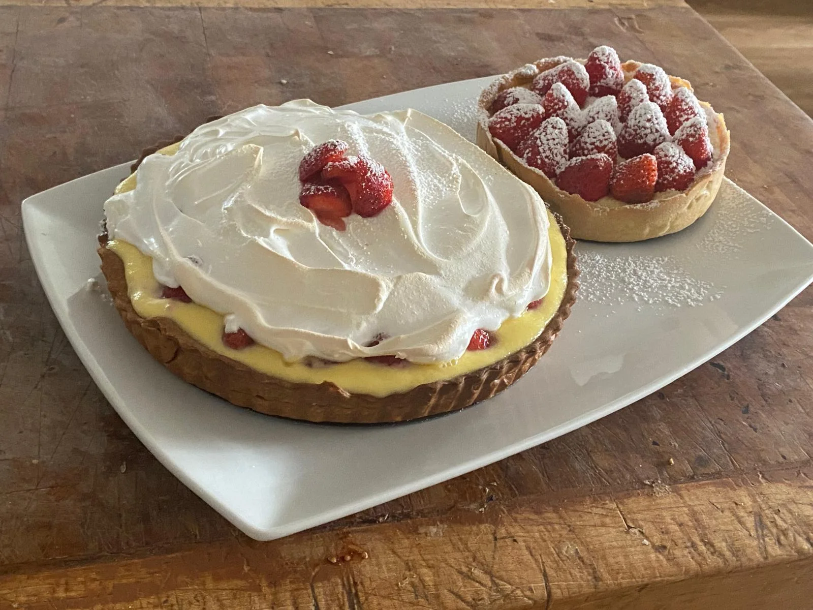 A full plate with strawberry tarts and cream-topped tart